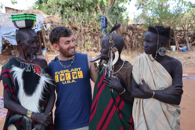 Un hombre con una camiseta azul con la palabra Everlast en ella posó con dos hombres africanos.